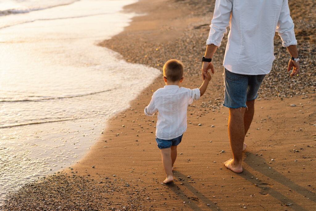 Father and baby play on the beach. Dad and him Child together en